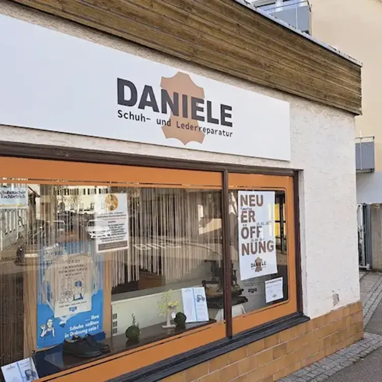 Außenschild „DANIELE Schuh- und Lederreparatur“ über dem Schaufenster, Ladenbeschilderung an der Fassade.